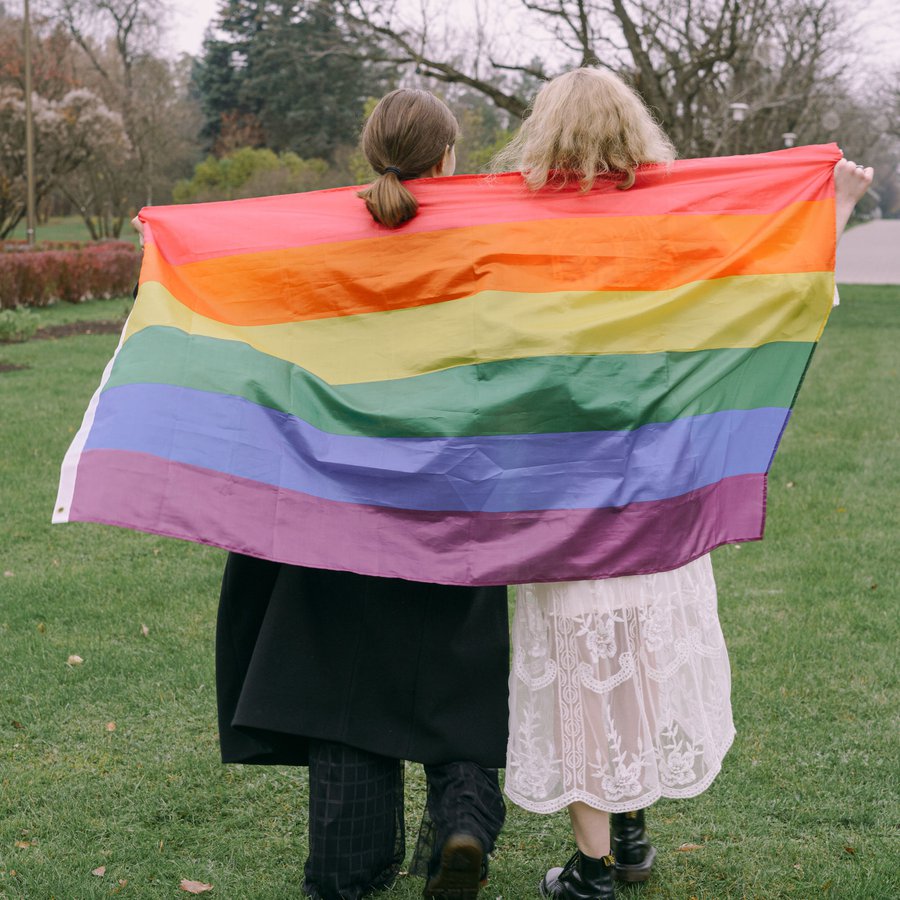 Zwei Jugendliche mit Regenbogenflagge